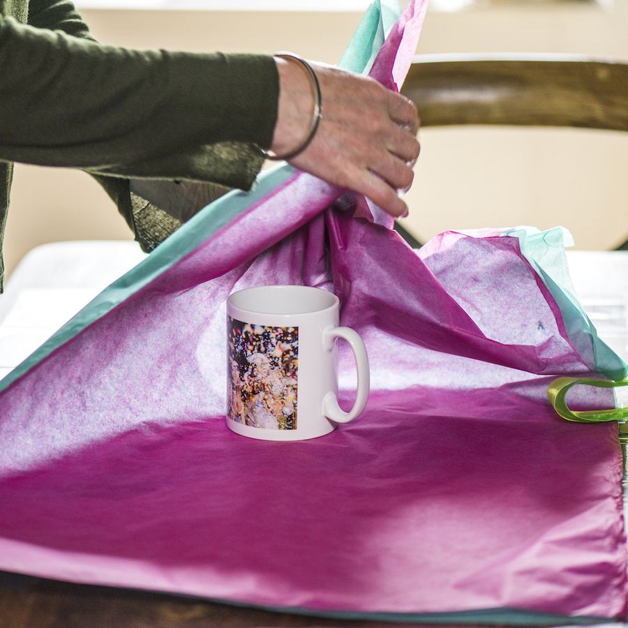 hands wrapping a mug using tissue paper
