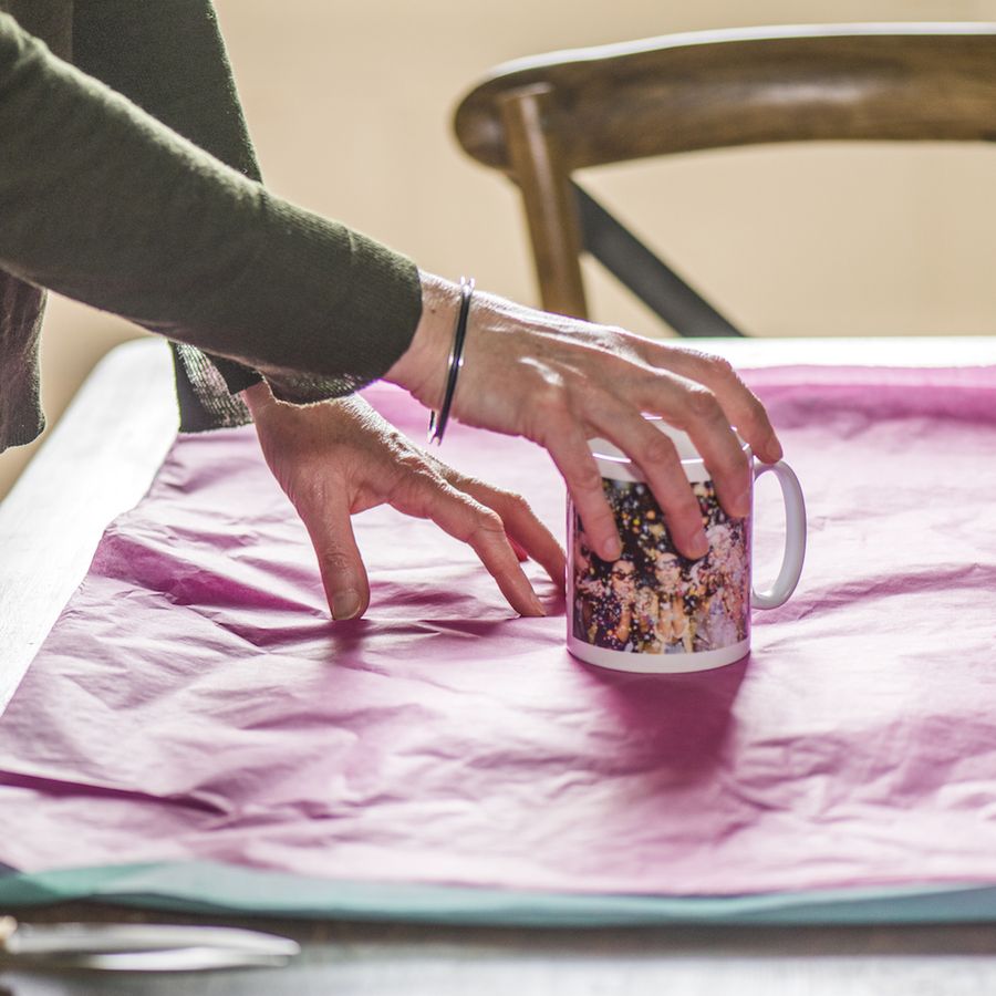 hands placing a mug on tissue paper ready for wrapping