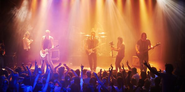Scène de concerts avec lumières jaunes et bleues et la foule déchaînée dans la fosse