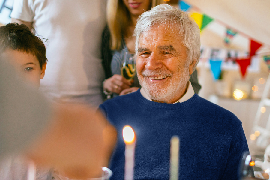 A grandfather smiling at his birthday celebration, illustrating 70th birthday gift ideas and birthday gifts for him from Photobox.