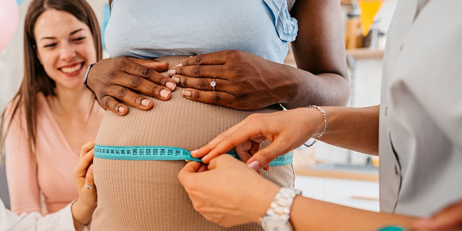 Women measuring their friend's pregnant belly with wool for the 