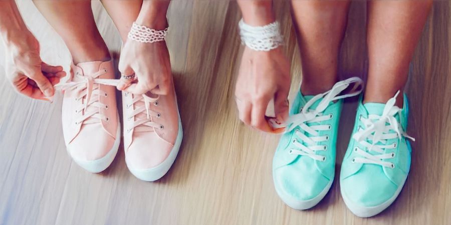 Two women at a baby shower with balloons under their shirts trying to tie their shoes, showing a hilarious baby shower game and baby shower idea from Photobox.