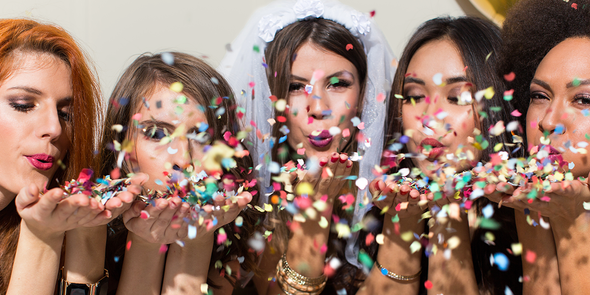 A woman in a veil blowing confetti with four of her girlfriends, gathering inspiration for hen party ideas and an unforgettable hen do with Photobox.