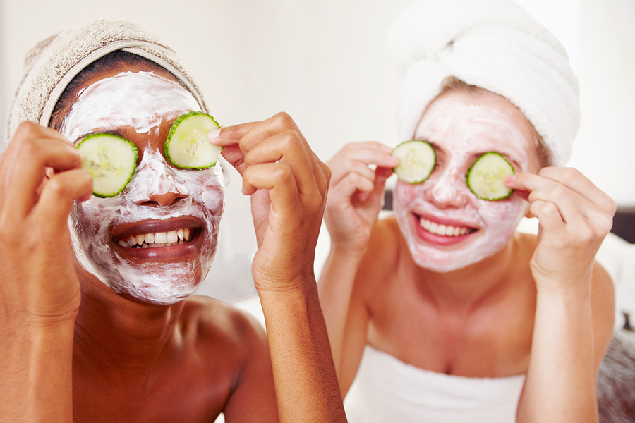 Two women with facemasks and cucumber slices on their eyes, a fun beauty-themed hen party idea for a celebration at home with Photobox.