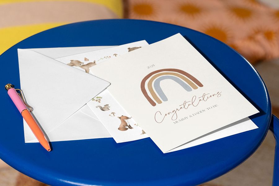 A newborn baby card on a blue table with a pen, perfect for drafting your message on what to write inside a newborn card from Photobox.