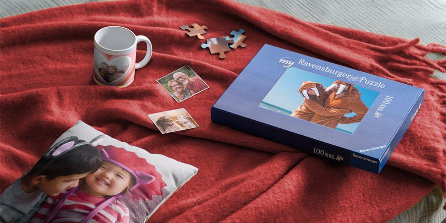 A variety of valentine's day gifts from Photobox, showing a personalised magnet, puzzle, and mug on a red blanket for romantic valentine's day ideas.