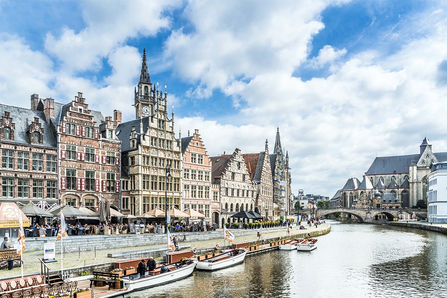A scenic view of the river in Ghent, Belgium, lined with medieval architecture, perfect for a romantic stroll.