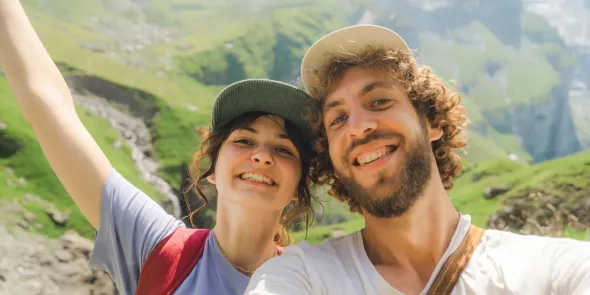 A smiling couple in a scenic hilly landscape enjoying a summer adventure, perfect for finding summer photo captions for Instagram or a Photobox photo book.