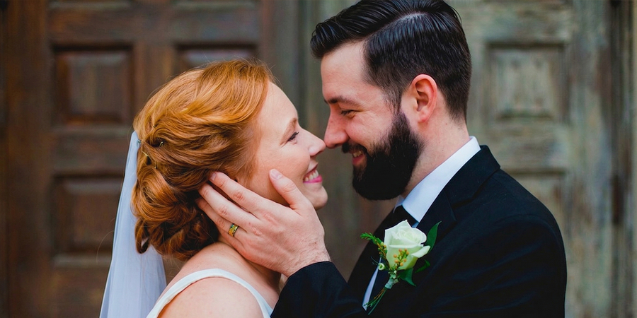 A bride and groom smile into each other’s eyes on their wedding day, with the groom’s hand on the bride’s cheek, inspiring wedding photo ideas from the ultimate wedding day photo checklist.