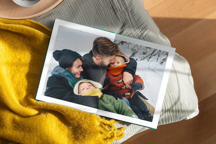 An open premium layflat photo book from Photobox showing a seamless two-page spread family photo, demonstrating high-quality photo book printing.