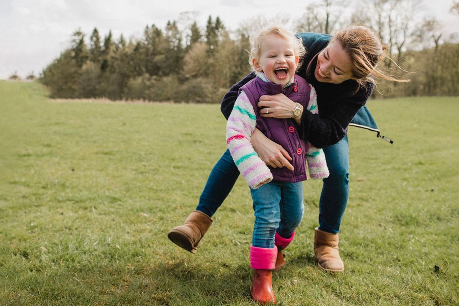 A mother and daughter smiling and playing outside while looking for what to write on a Valentine's Day Instagram post for family and valentines gifts from Photobox.