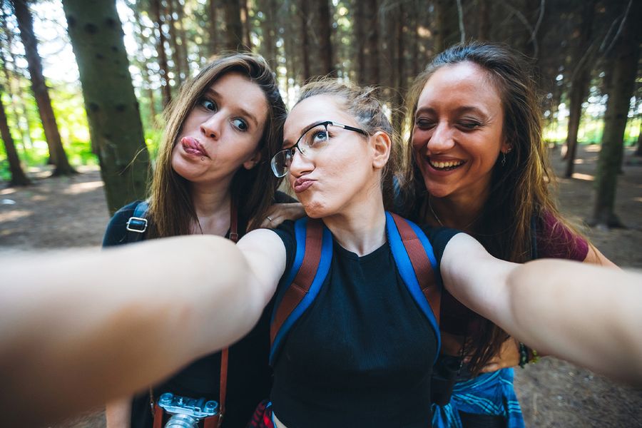 Three girlfriends smiling together and sharing ideas on what to write in a Valentine's Day card for friends to go with their galentines presents and valentines gifts from Photobox.