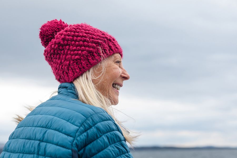 A happy woman smiling alone outside while searching for what to write on her Valentine's Day Instagram post about self-love and finding Valentine's day ideas and valentines gifts for herself from Photobox.