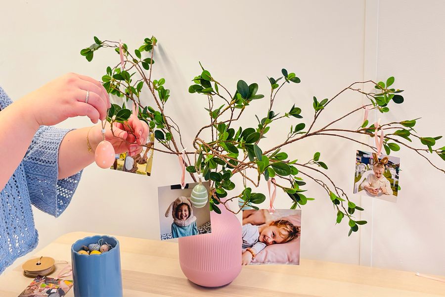 Someone adding decorative Easter eggs to a tree with photo prints, showing DIY Easter centerpiece ideas and handmade Easter decor with Photobox.