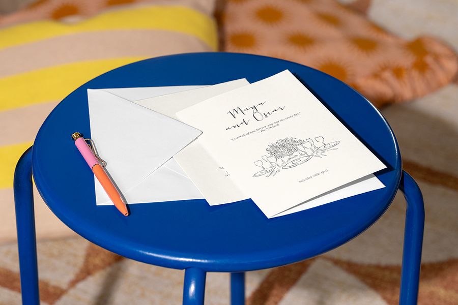 An illustrated Photobox personalised wedding invitation displayed on a stool, inspiring original wedding invitation wording and wedding card messages with a romantic film quote.