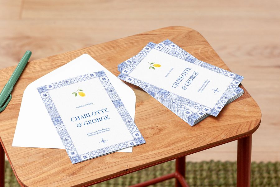 A Photobox personalised wedding invitation with a Mediterranean tile border and lemon design displayed on a table, inspiring unique wedding invitation wording and wedding card messages.