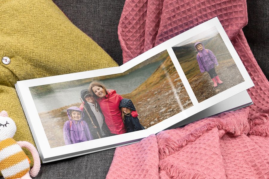An open Photobox photo book showing smiling children by a lake.