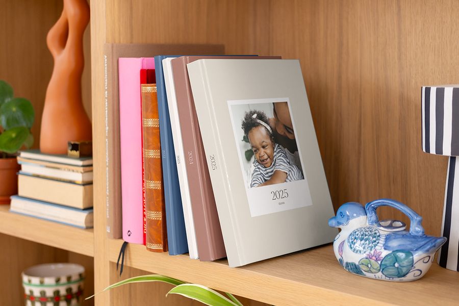 A row of colourful, patterned Photobox yearly photo books and annual photo albums displayed neatly on a bookshelf.