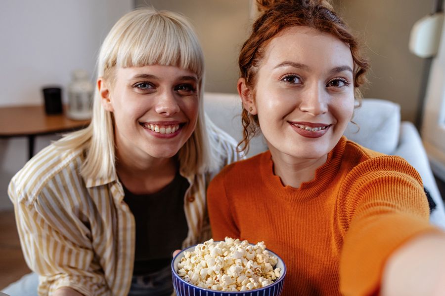 Two best friends sharing popcorn for a cozy Galentine's Day movie night, proving that Valentine's Day is also for friends to enjoy together with Photobox.