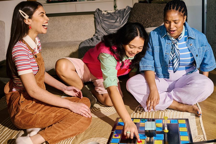 Three best friends enjoying a board game for Galentine's Day, a fun way to spend Valentine's Day with friends and make Photobox memories.