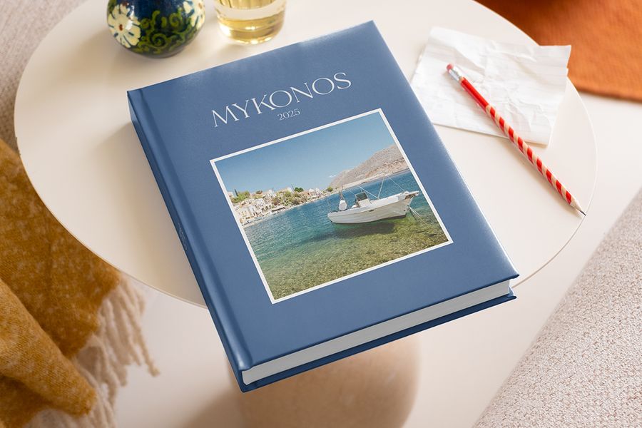 Ideas for what to write in a photo album shown on a Mykonos 2025 travel book, with a pencil ready to record memories alongside beautiful phrases for photo albums.