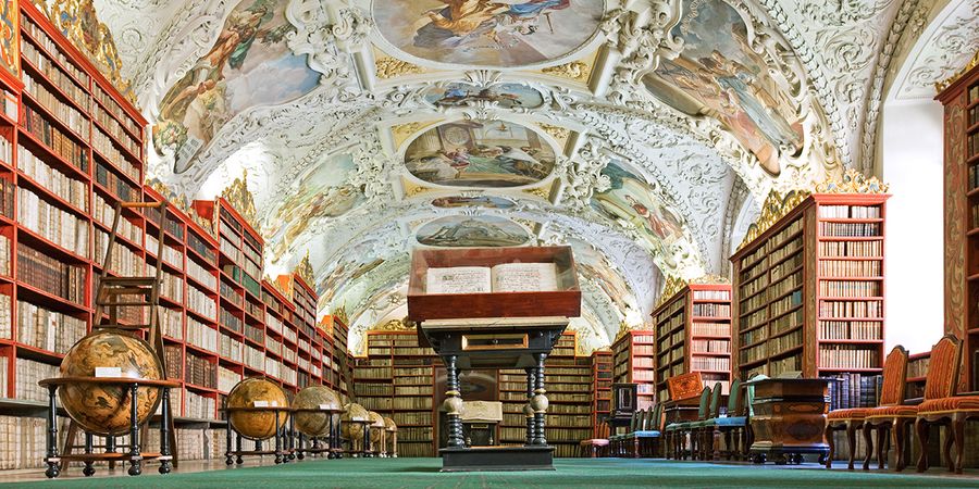 The Theological Hall of the Strahov Library in Prague, showcasing stunning stucco and globes as part of a literary travel bucket list with Photobox.