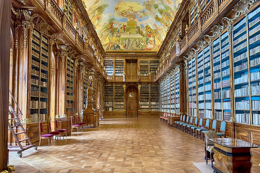 The Philosophical Hall of the Strahov Monastery Library in Prague, featuring soaring ceilings and walnut wood shelves, an essential stop for literary travel with Photobox.