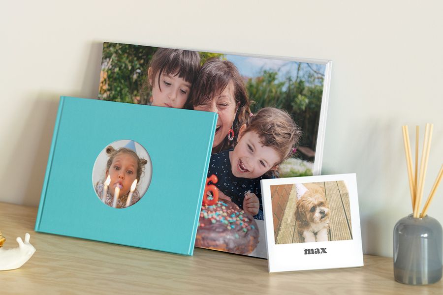 Three birthday photobooks from Photobox: one with a grandmother and grandkids, a first birthday photo album of a little girl blowing candles, and a birthday memory book featuring a dog called Max.