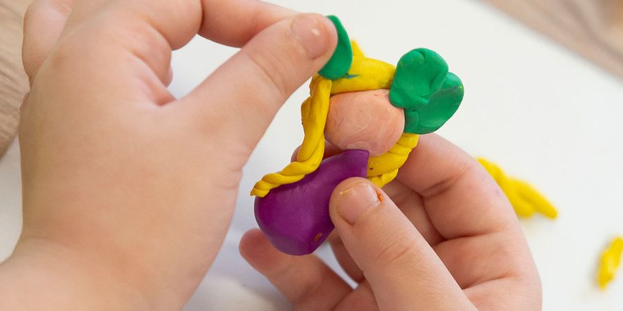 Guests at a baby shower showing off their sculpting skills by making Play-Doh babies, illustrating creative baby shower games and baby shower ideas from Photobox.