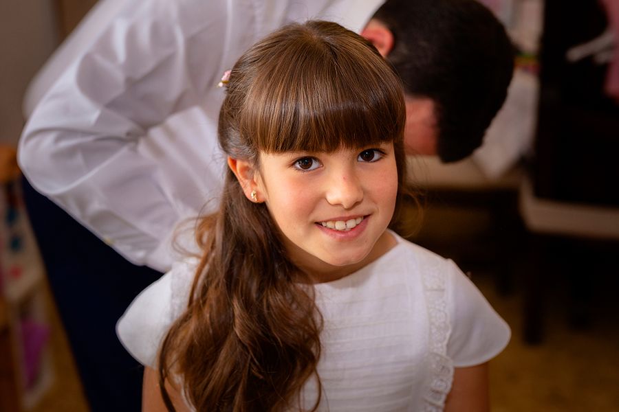A young girl in a white formal communion dress posing for a portrait, highlighting first holy communion dresses and first holy eucharist preparations with Photobox.