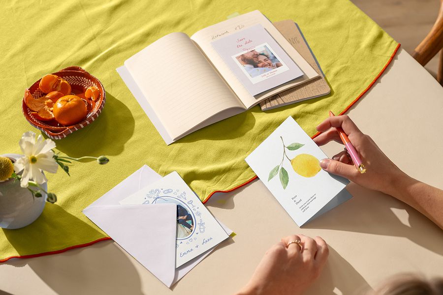 A collection of trending wedding invitations and cards on a bold citrus tablecloth, showcasing the top 2026 wedding trends and colour theme wedding ideas with Photobox.