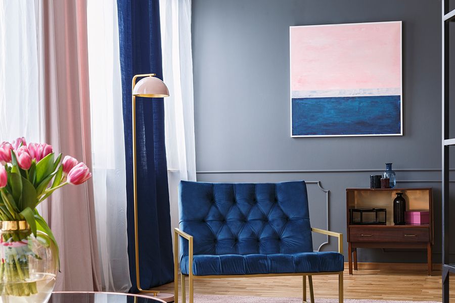 A navy and pink living room featuring a blue velvet sofa, colorful curtains, and pink tulips, showcasing renter-friendly curtains and home decor hacks with Photobox.