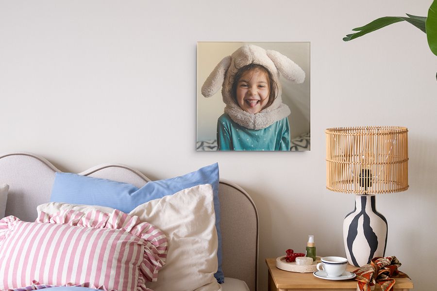 A retro print of a young girl displayed in a colourful bedroom, showing how to hang pictures without nails and create renter-friendly wall decor with Photobox.