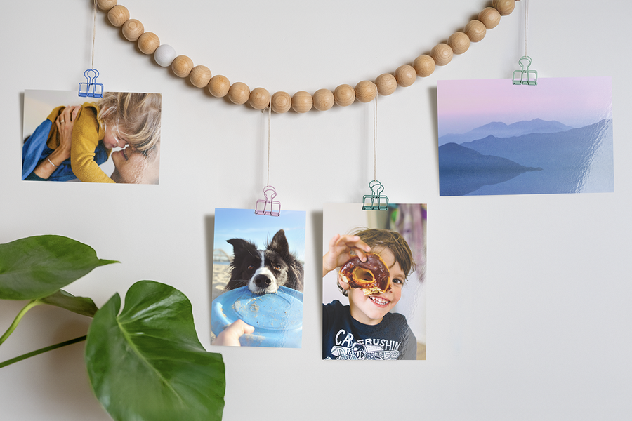 Creative ways to display Photobox photo prints, with family photo prints of a dog, a child with a doughnut and a landscape hanging from a beaded string with clips, inspiring photo printing ideas and ways to print photos online.