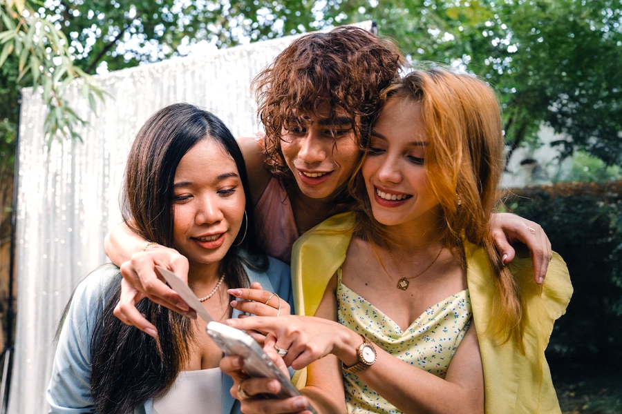 Three friends in formal wedding outfits taking part in a wedding photo scavenger hunt, inspiring Photobox wedding games and fun wedding games for guests.