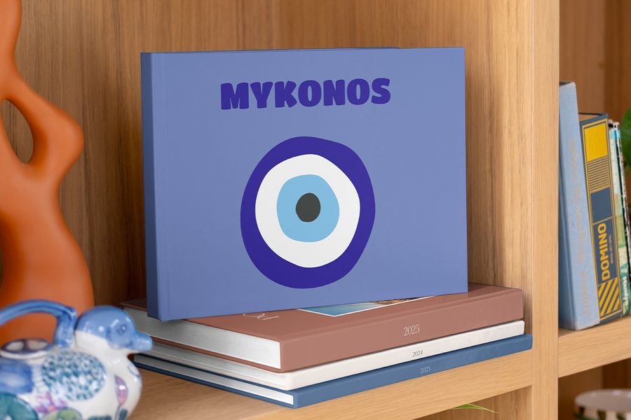 A Photobox travel coffee table photo book with a striking blue cover and an evil eye design inspired by Greece, created as a standout coffee table book for your living room.