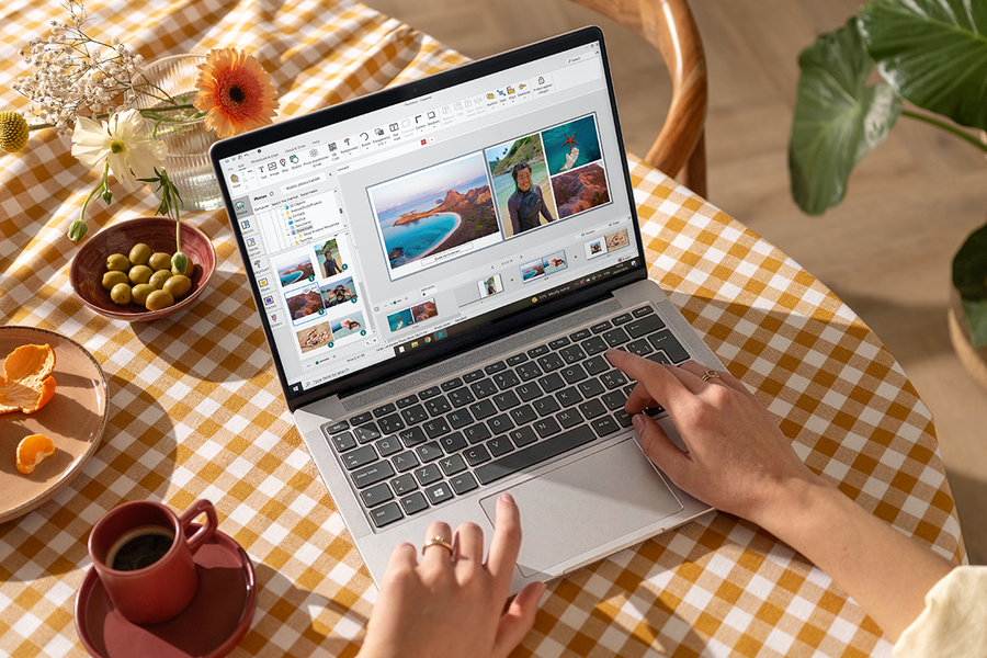 Someone using the Photobox Desktop App on a laptop at their kitchen table, with a coffee mug and olives nearby, inspiring photo book software and the best photo book maker for creative projects.