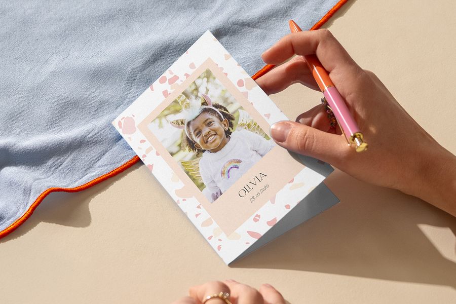 Someone writing a child’s birthday invitation, inspiring Photobox children’s birthday party ideas and personalised children’s party invitations.