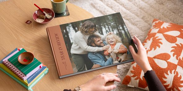 A year in review Photobox coffee table photo book with an attractive family photo on the cover, displayed on a coffee table as inspiration for a custom coffee table book.