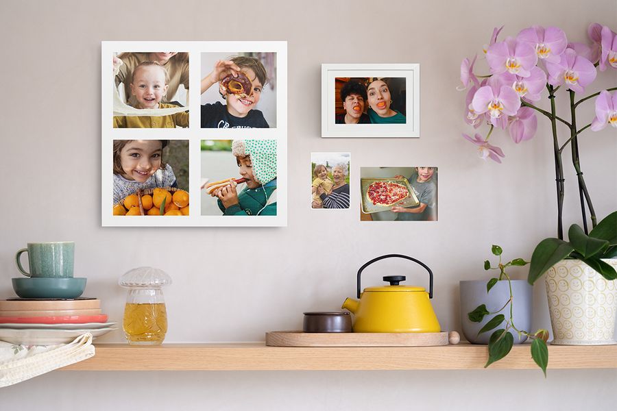 A wooden shelf styled with homely decor sits beneath a personalised photo collage of children, a framed funny photo print and two family photo prints, showing creative ways to bring photo prints to your walls.