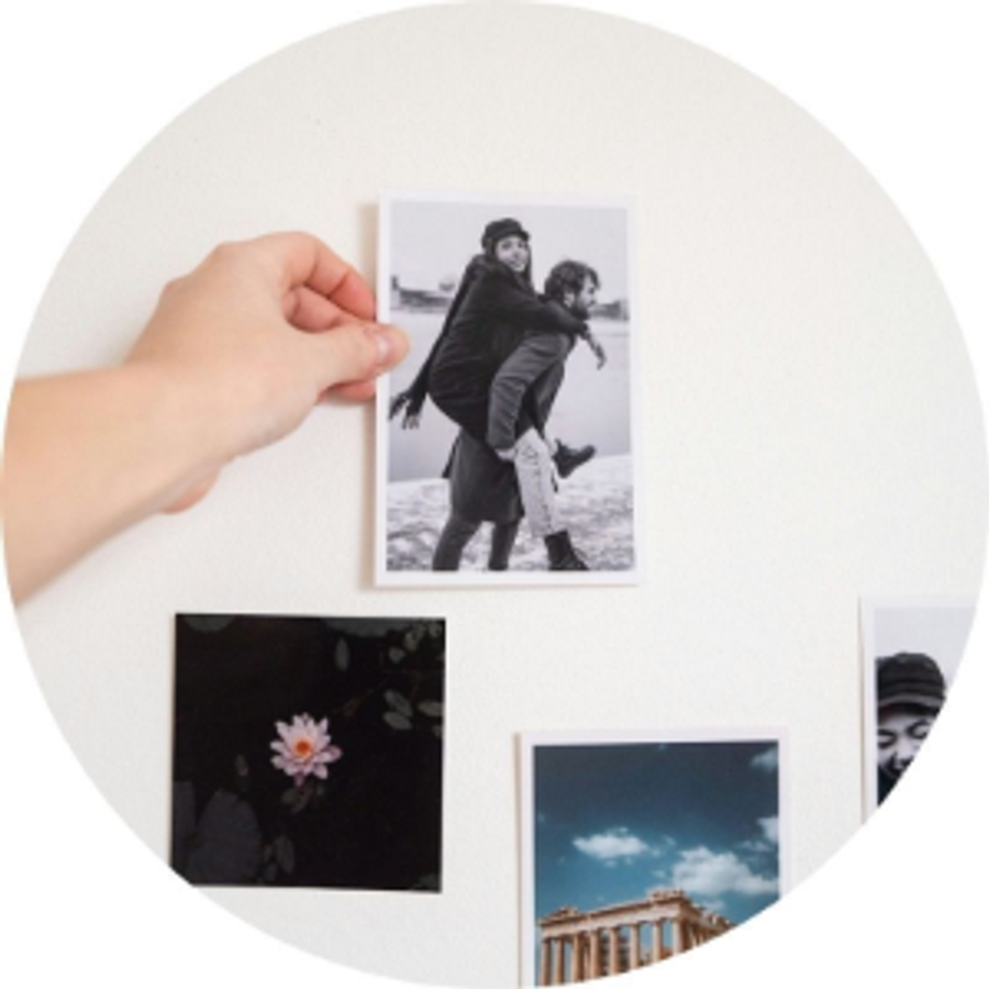 A hand holds a photo print of a couple beside other photo prints, illustrating Andrea’s proposal story and a meaningful memory-filled proposal idea from Photobox.